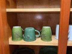 Contents of cupboard: Dansk stoneware dinnerware, green glazed pinecone motif dinnerware