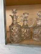 Four pressed pattern glass cruets and one syrup pitcher