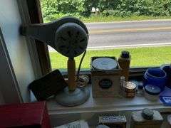 Early electric hair dryer and advertising tins and bottles on rear shelf of windowsill
