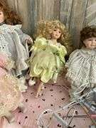 Five porcelain collector dolls, doll stands, cushion