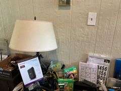 Contents of desk top and underneath: metal lamp, cable modem, twin, puzzles, office supplies, tape, waste cans, CDs, misc