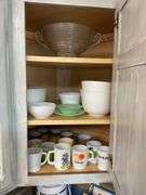 Contents of cupboard: vintage coffee mugs, jadeite glass, milk glass mixer bowls, 2-handle ribbed glass bowl