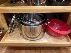 Contents of cupboard: cookware, steamer basket, lid rack