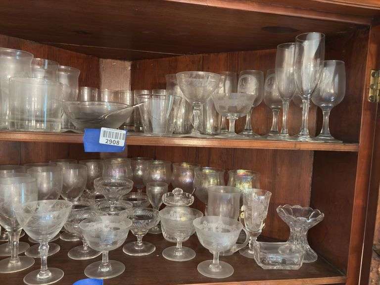 Contents of two shelves: engraved and iridescent stemware, glass serving pcs, salt/pepper shakers