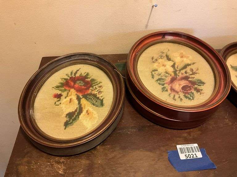 Four oval frames containing floral needlepoint
