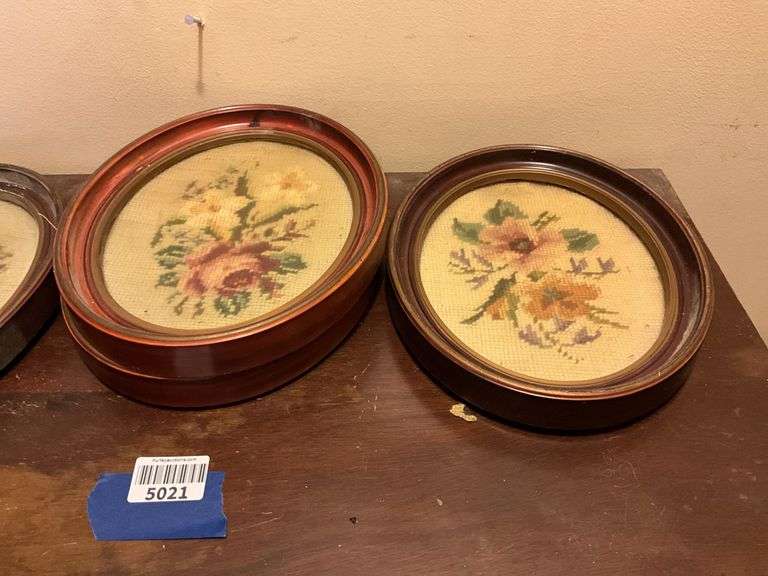 Four oval frames containing floral needlepoint