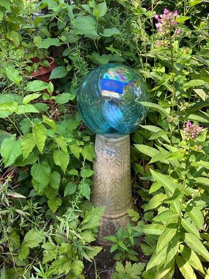 Blue gazing ball on cement pedestal