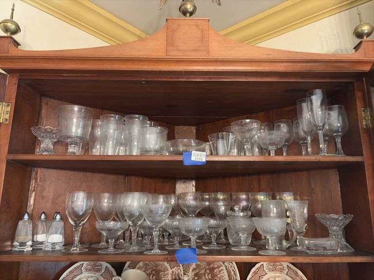 Contents of two shelves: engraved and iridescent stemware, glass serving pcs, salt/pepper shakers