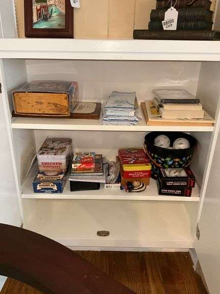 Contents of two shelves: puzzle, road maps, games, ping pong balls, misc