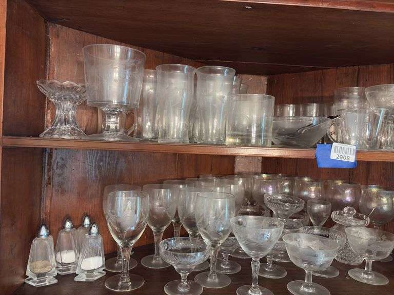 Contents of two shelves: engraved and iridescent stemware, glass serving pcs, salt/pepper shakers