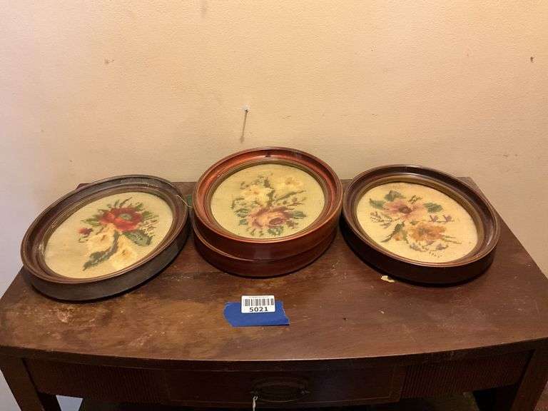 Four oval frames containing floral needlepoint