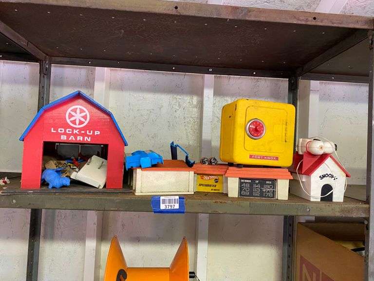 Contents of shelf: toys including Playskool Barn, Hot Wheels Speedometer playset, Fort Knox combination safe, Snoopy doghouse vaporizer