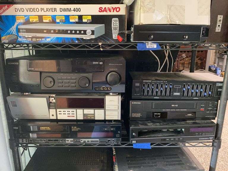 Contents of shelf: stereo receivers, VHS players, graphic equilizer