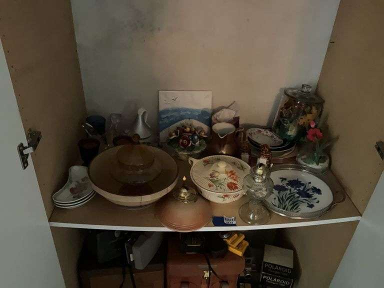 Contents of shelf: glass oil lamp, antique china bone dishes, yellow ware mixing bowl, amber glass covered dish, decorated serving tray, decor items, misc
