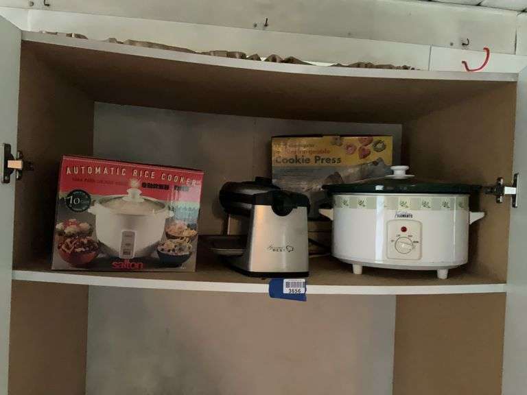 Contents of shelf: rice cooker, waffle maker, slow cooker, cookie press