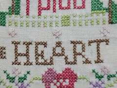 (Q) Framed Counted Crosstitch Piece Featuring Saying "Home Is Where The Heart Is"