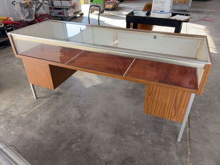 Glass Display Case, Lighted, 70 1/2” long X 24” wide X 33 1/2” tall, 4 hinged lockable doors on back, unknown if light work, Brown Wood Grain Formica