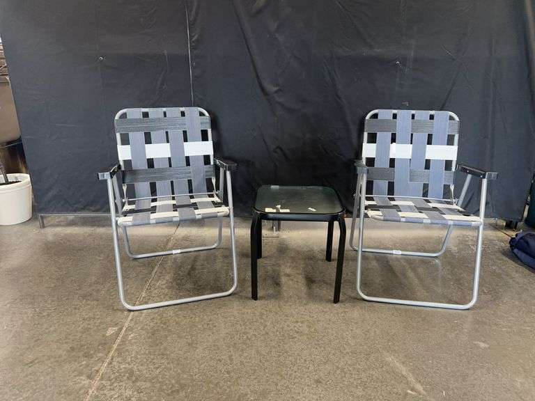 Two gray folding chairs and small glass top table