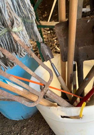 Plastic barrel containing handled tools-shovels, potato fork, rake, pruning shears, pry bar