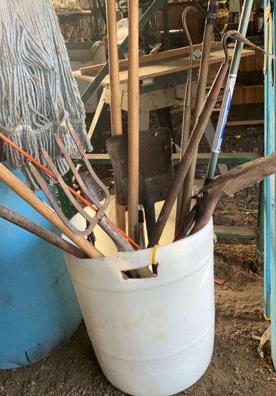 Plastic barrel containing handled tools-shovels, potato fork, rake, pruning shears, pry bar