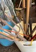 Plastic barrel containing handled tools-shovels, potato fork, rake, pruning shears, pry bar