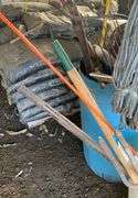 Plastic barrel containing handled tools-shovels, potato fork, rake, pruning shears, pry bar