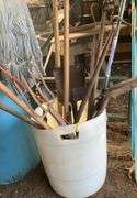 Plastic barrel containing handled tools-shovels, potato fork, rake, pruning shears, pry bar