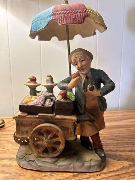Vintage porcelain or ceramic figurine depicting an old man with a fruit cart, possibly a fruit vendo