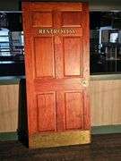 Reddish-Brown Wood Restroom Door, Brass Kick Plate