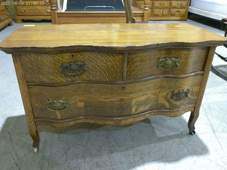 454 - Antique tiger oak serpentine dresser on casters. Pulls are not original, finish is very nice b
