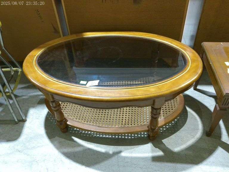 502- Oval glass top coffee table. Lower shelf is cane. 41" long