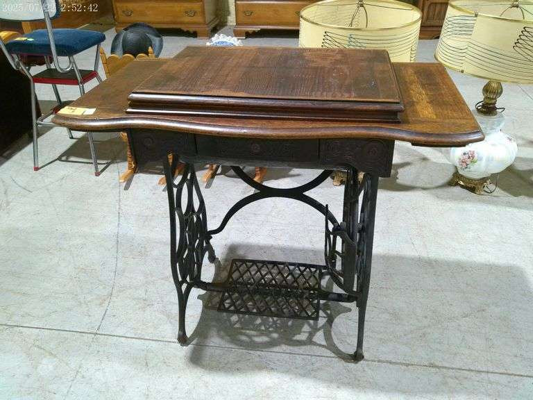 562 - Treadle sewing machine cabinet (no sewing machine). Has 4 original casters, some damage to woo