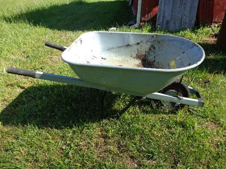 Wheelbarrow. Has a flat tire. Located by building.