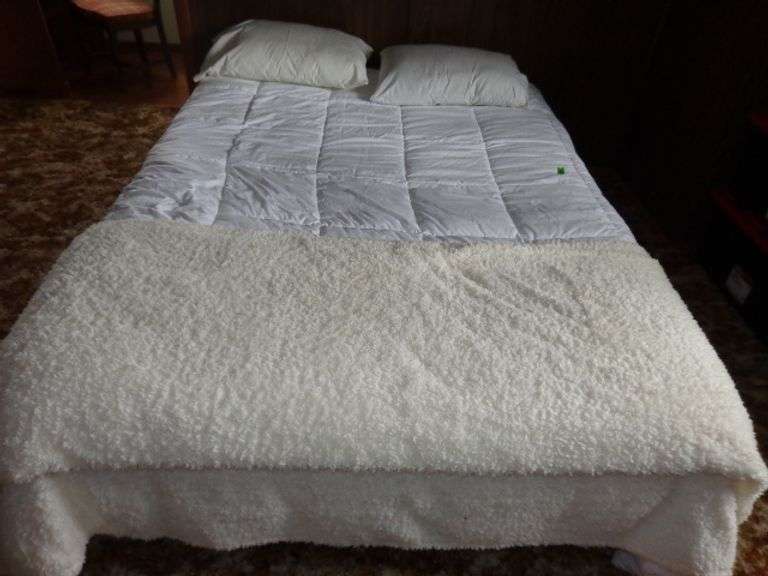 Queen box springs and mattress on frame, white comforter and blanket, pillows