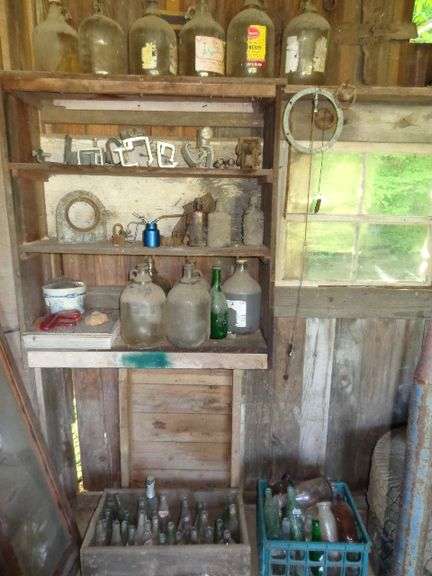 Assorted bottles and glass jugs. Includes wooden crate of bottles, plastic crate of bottles, wall of