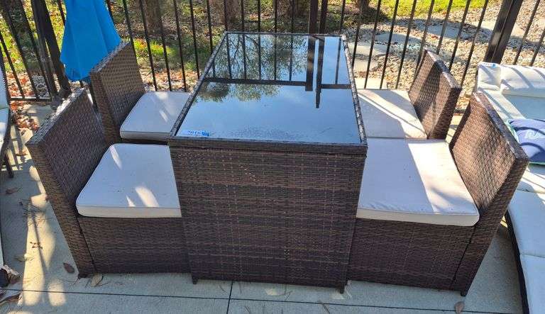 Glass top patio table with four self-storing chairs with cushions