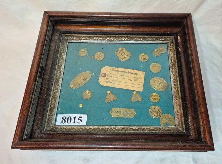 Collection of brass tags, possibly employee badges, in antique deep Walnut frame