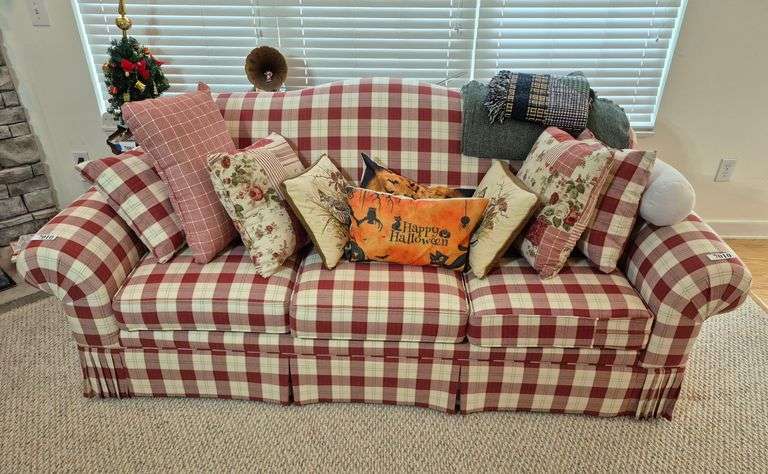 Red checkered sofa with many accent pillows and two throws