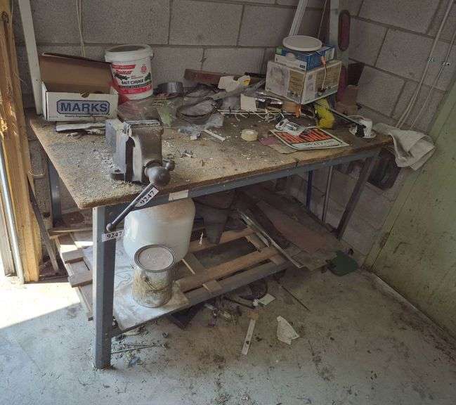 Metal workbench with particle board top, vintage bench vise, propane tank, miscellaneous contents