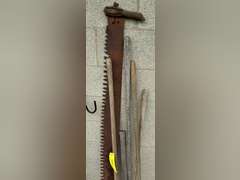 Two man saw, has damaged and a missing handle, double bladed ax, two hose, rake