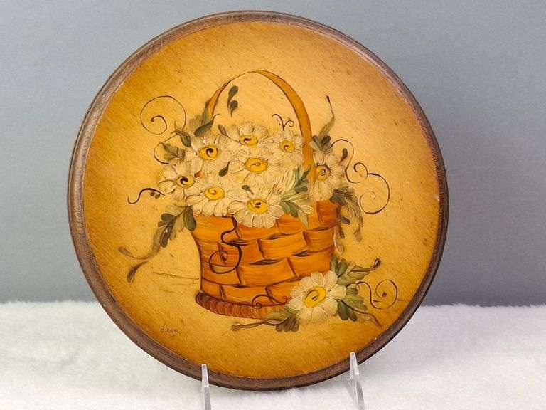 ROUND WOODEN PLAQUE WITH A HAND-PAINTED BASKET FILLED WITH DAISIES, SIGNED FRAN '75, 9.5"W.