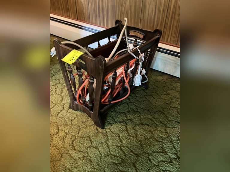 small magazine rack with extension cords and books