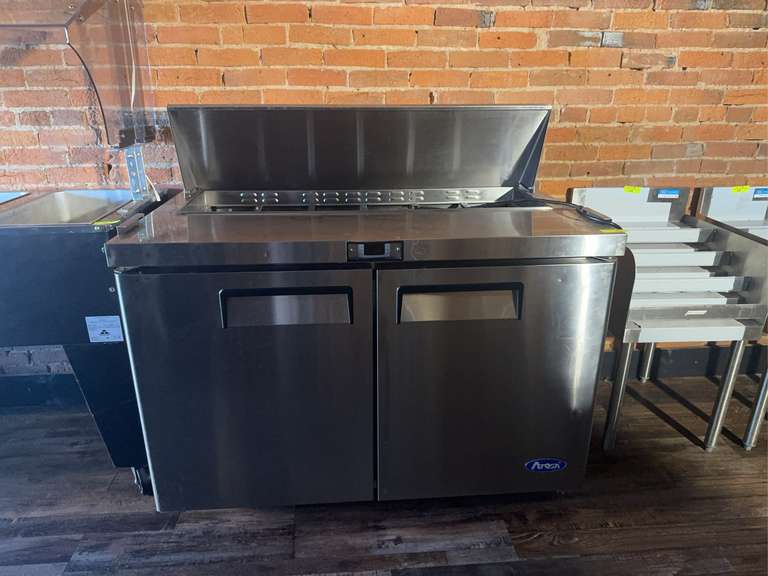 Atosa Sandwich/Salad Top Refrigerator, two-section, 48-1/5"W × 30"D x 41-3/8"H, includes (12) 1/6 stainless steel pans, rear-mounted, self-contained refrigeration, 13.4 cu. ft., (2) solid hinged self-closing doors, digital temperature control, 33° to 40°F temperature range. (2) adjustable shelves, 10" poly cutting board, ventilated refrigeration, automatic evaporation, air defrost, stainless steel interior & exterior, galvanized steel back, 3" casters, R290 Hydrocarbon refrigerant, 1/7 HP, 115v/60/1-ph, 2.3 amps, cord, NEMA 5-15P, cETLus, ETL-Sanitation Weight: 276 Ibs total