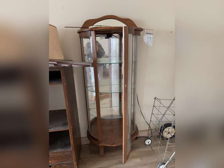 Wooden curio cabinet with a curved glass door and mirrored back