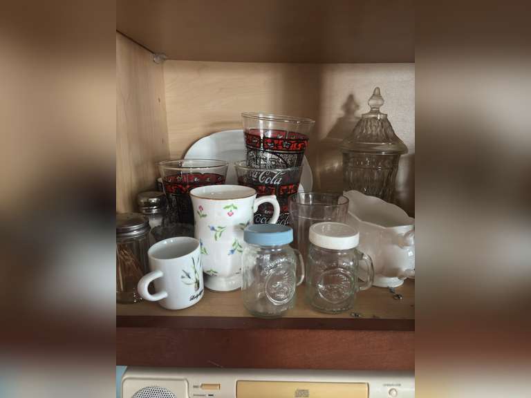 Shelf of salt and pepper, mugs, Coca Cola glasses, and organizer