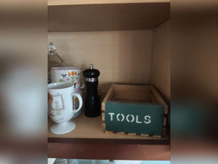 Shelf of salt and pepper, mugs, Coca Cola glasses, and organizer