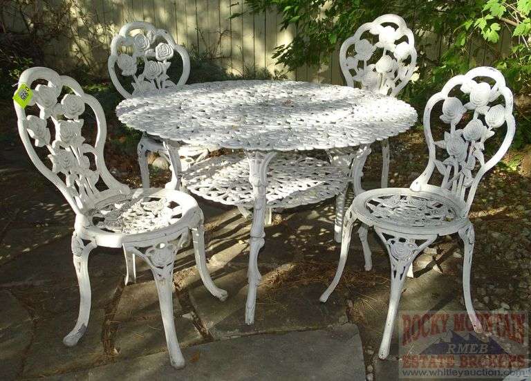 Victorian Style Cast Aluminum Patio Table, Umbrella Stand & 4 Chairs. Table is 41" diameter & the chairs have fancy floral decoration.