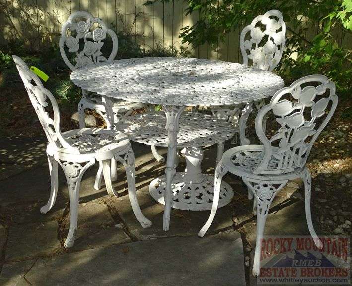 Victorian Style Cast Aluminum Patio Table, Umbrella Stand & 4 Chairs. Table is 41" diameter & the chairs have fancy floral decoration.