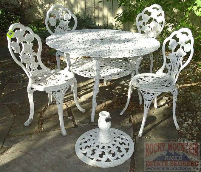 Victorian Style Cast Aluminum Patio Table, Umbrella Stand & 4 Chairs. Table is 41" diameter & the chairs have fancy floral decoration.