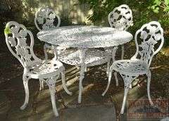 Victorian Style Cast Aluminum Patio Table, Umbrella Stand & 4 Chairs. Table is 41" diameter & the chairs have fancy floral decoration.